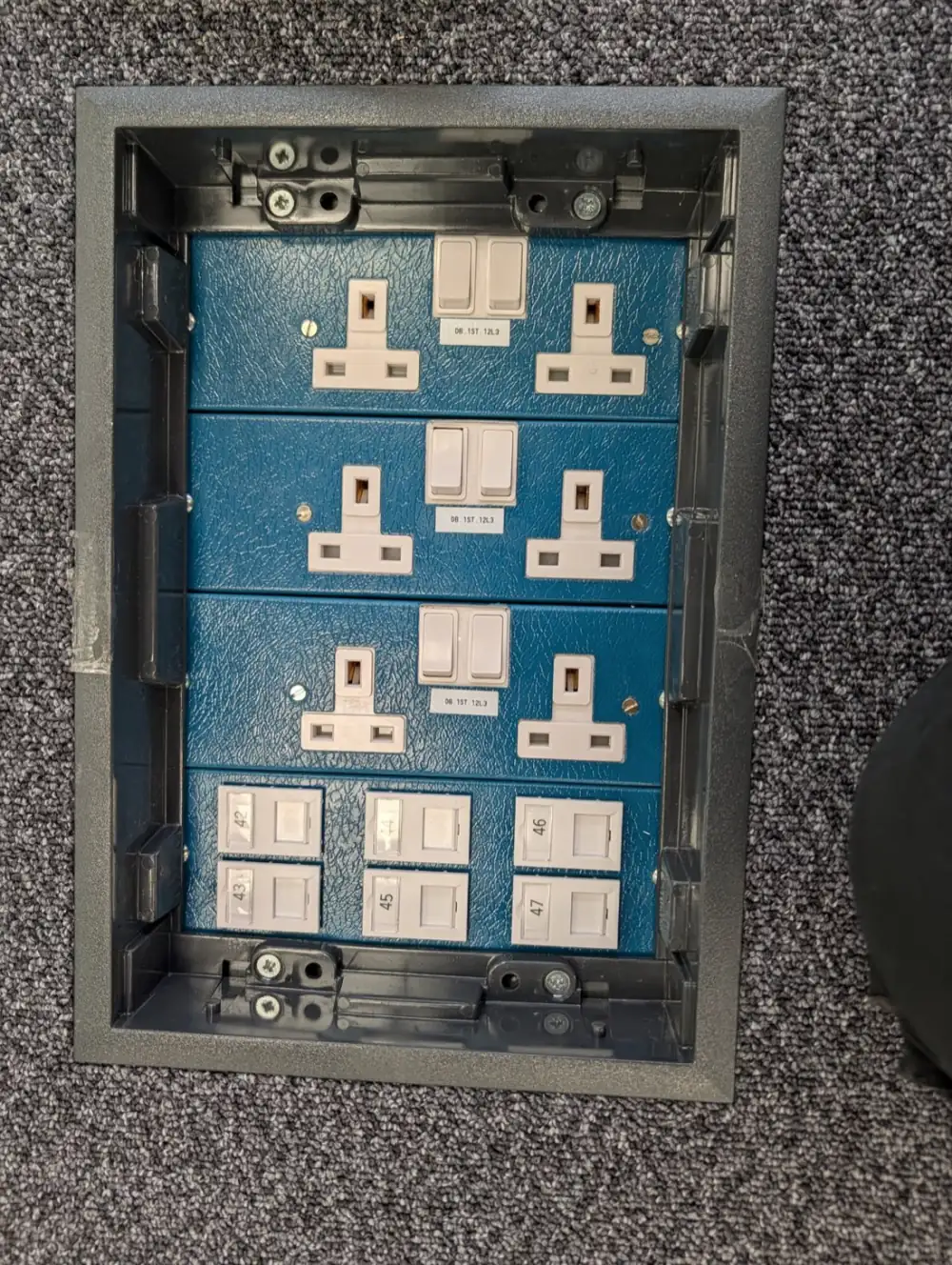 Recessed floor box with sockets and numbered data outlets in a commercial fit-out